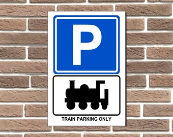Può includere: Un cartello bianco con un cartello di parcheggio blu e una silhouette nera di un treno. Il cartello recita "Train Parking Only".