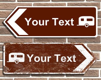 Op de afbeelding: Twee bruine borden met witte pijlen die naar links wijzen. Het bovenste bord heeft een wit kampeerwagenpictogram en de tekst "Your Text". Het onderste bord is verweerd en heeft een wit kampeerwagenpictogram en de tekst "Your Text".