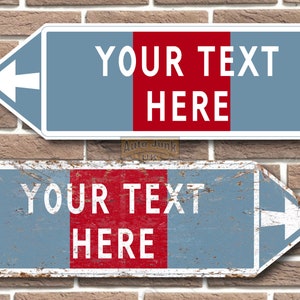 Può includere: Due cartelli in metallo dall'aspetto usurato. I cartelli sono blu con una striscia rossa al centro. I cartelli hanno frecce bianche che puntano a sinistra e il testo "YOUR TEXT HERE" in bianco.