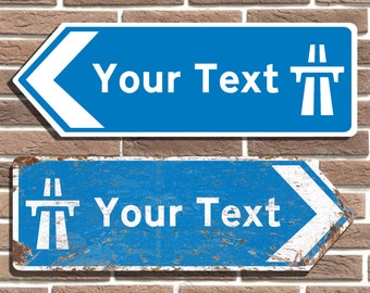 May include: Two blue and white road signs with white arrows pointing left. The top sign is new and the bottom sign is distressed and rusty. Both signs have the text "Your Text" and a symbol of a motorway overpass.