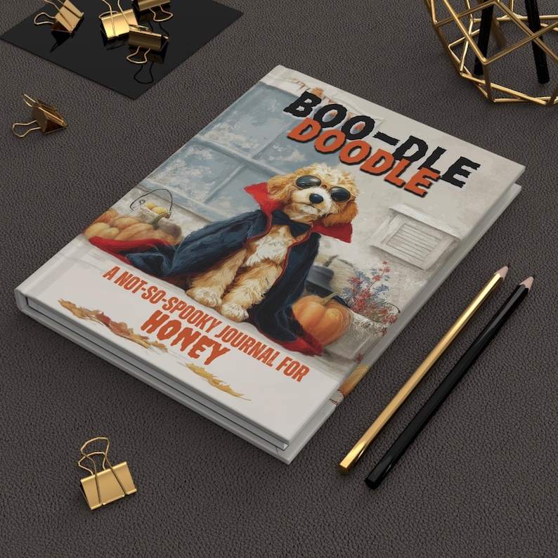 May include: A hardcover journal titled "Boo-Doodle" with a cartoon dog in a vampire costume. The journal cover features a dog wearing sunglasses and a cape, with a pumpkin and the text "A Not-So-Spooky Journal for Honey."
