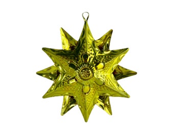 May include: A gold-coloured metal star ornament with a decorative design. The star has eight points and a loop at the top for hanging.