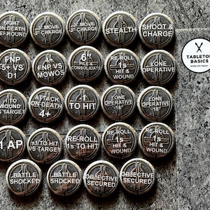 May include: A set of twenty-four bronze-coloured game tokens, each with engraved text and symbols. The circular tokens feature phrases like "Fight on Death", "Move", and "Objective Secured" in white lettering. A logo in white and black is visible in the upper right corner.