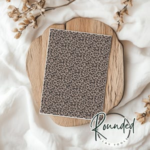 May include: A sheet of brown and black leopard print patterned paper. The paper is on a wooden surface.