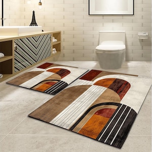 May include: Two brown and white geometric bathroom rugs with abstract shapes in shades of brown, orange, and red. The rugs are placed on a tiled floor in a bathroom.