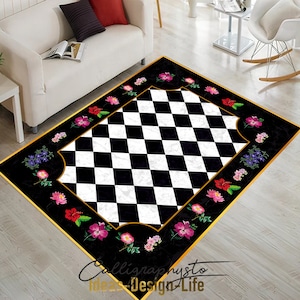 Op de afbeelding: Zwart-wit geblokt tapijt met een gouden rand en bloemmotieven. Het tapijt heeft een marmerachtige textuur en heeft roze, paarse en rode bloemen.