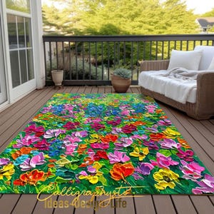 May include: A colorful rug with a floral design. The rug features a variety of flowers in shades of pink, purple, red, yellow, and orange. The flowers are painted in a thick, textured style, giving the rug a three-dimensional look. The rug is set on a wooden deck, with a wicker chair and potted plants in the background. The rug has the text "Calligraphysto Ideas-Design Life" at the bottom.