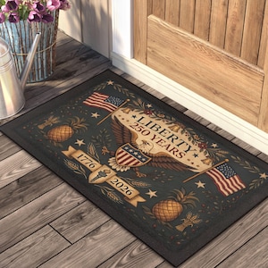 May include: Rectangular doormat with a dark background featuring an eagle, American flags, pineapples, and the text "LIBERTY 250 YEARS" and "1776 2026". The design is patriotic and decorative.