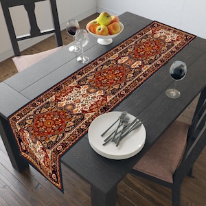 Könnte beinhalten: Ein rechteckiger Tischläufer mit einem detaillierten, komplexen Muster in den Farben Dunkelrot, Schwarz, Creme und Gold. Das Design zeigt sich wiederholende geometrische und florale Motive, die an Teppichmuster erinnern, flach auf einem dunklen Tisch.