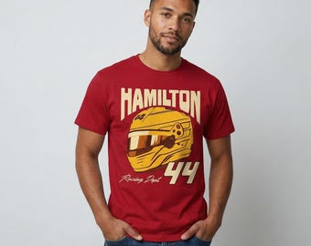 May include: A maroon t-shirt with a yellow racing helmet graphic and the name "HAMILTON". The number "44" is below the helmet, with "Racing Dept" underneath. The shirt is worn by a person.