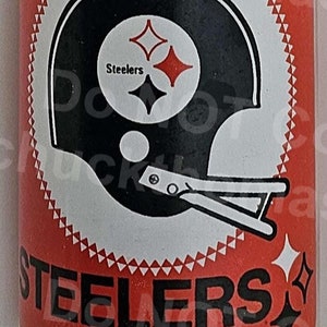 May include: A clear glass bottle with a red label featuring the Pittsburgh Steelers logo. The label reads "Pittsburgh Steelers" and has a black and white helmet with three stars. The bottle is 12 ounces (1 pint) and is a product of Beverage Management, Inc. 1971.