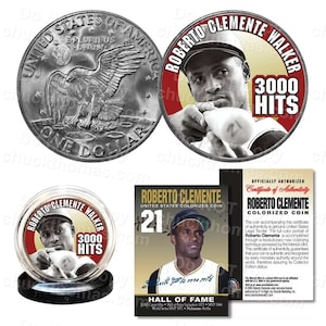 May include: A silver dollar coin with an eagle on the front and a colorized image of Roberto Clemente on the back. The coin is in a plastic case with a certificate of authenticity. The certificate is gold and black with the text "Roberto Clemente Colorized Coin" and "Officially Authorized".
