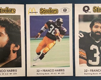 May include: Three vintage trading cards featuring Franco Harris, a former running back for the Pittsburgh Steelers. The cards are white with black and yellow text and a black and white photo of Harris in a Steelers uniform. The text on the cards reads "32 - Franco Harris, Running Back, Ht: 6-2 Wt: 225".