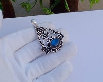 May include: A silver pendant with an intricate design featuring a blue labradorite gemstone.