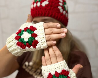 May include: A set of white crocheted fingerless gloves with red and green accents. The gloves feature a large, colorful flower design.