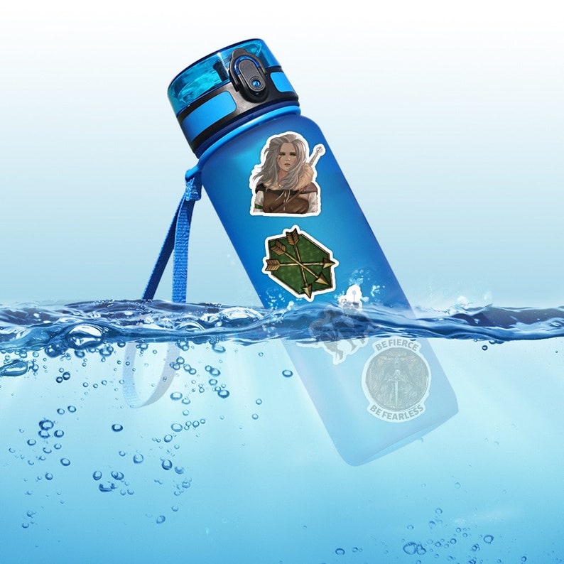 May include: A blue water bottle with a black lid and a carrying strap. The bottle has three stickers on it: a woman with long blonde hair, a green arrow design, and a round sticker with the words "Be Fierce Be Fearless".