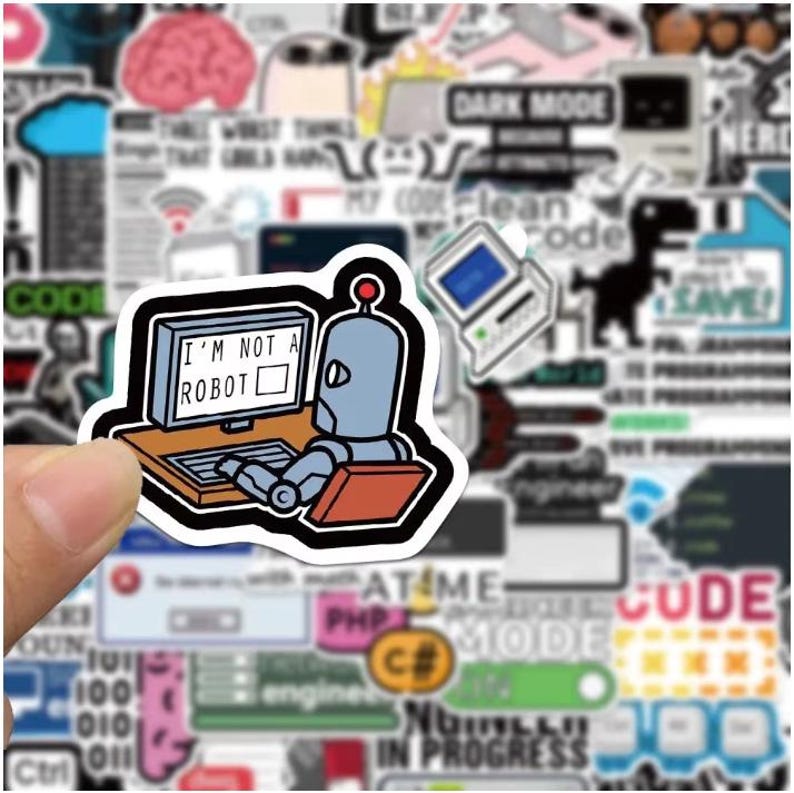 Peut inclure: Un autocollant repr&eacute;sentant un robot de dessin anim&eacute; devant un ordinateur avec le texte "I'M NOT A ROBOT". Le robot est gris avec une lumi&egrave;re rouge sur la t&ecirc;te. L'autocollant est entour&eacute; d'autres autocollants sur le th&egrave;me de la technologie, dont "DARK MODE".