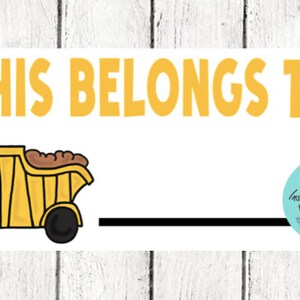 May include: A rectangular label featuring the yellow text THIS BELONGS TO at the top. Below the text is a yellow dump truck graphic carrying brown dirt, followed by a long black horizontal line for writing a name. A teal circular badge says Instant Download.