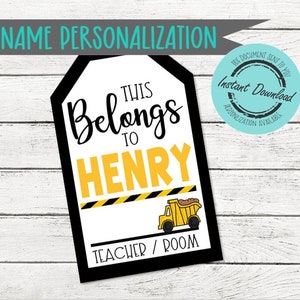 May include: A rectangular tag with a black border featuring the text This Belongs To HENRY in black and yellow lettering. Below the name is a yellow and black caution stripe graphic and a yellow dump truck illustration with the text TEACHER / ROOM.