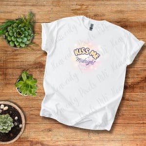Camiseta "Bésame a medianoche" con letras de burbujas y diseño de orbe luminoso rosa y morado para Año Nuevo y Nochevieja.