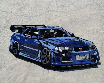 Könnte beinhalten: Ein blauer Autoteppich mit einem detaillierten Design eines Sportwagens. Das Auto hat einen schwarzen Spoiler, schwarze Räder und eine schwarze Frontstoßstange. Der Teppich ist aus einem weichen, plüschigen Material gefertigt.