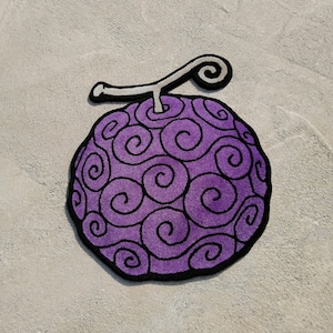 May include: Purple and black rug with a swirl design resembling a fruit. The rug has a stem with a curl at the end.
