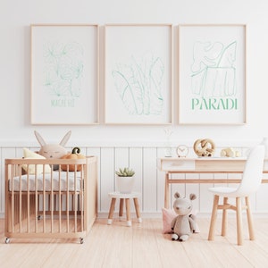 Può includere: Tre stampe incorniciate con disegni a linea verde di piante tropicali. Le stampe sono appese a una parete bianca sopra una culla di legno e una scrivania. Il testo sulle stampe recita "Mache Fle" e "Paradi".