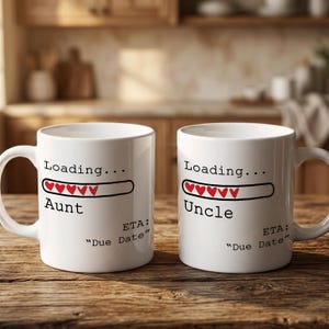 May include: Two white ceramic mugs featuring black text and a red heart-shaped loading bar. The left mug reads Loading... Aunt, and the right mug reads Loading... Uncle. Both mugs include the text ETA: "Due Date" printed in black.