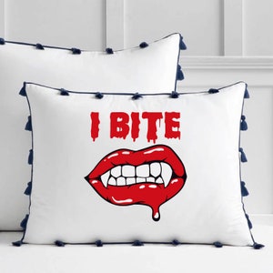 K&ouml;nnte beinhalten: Wei&szlig;es Kissen mit blauem Besatz und Quasten. Das Kissen zeigt eine rote und wei&szlig;e Grafik eines Vampirmundes mit Z&auml;hnen und dem Text "I Bite".