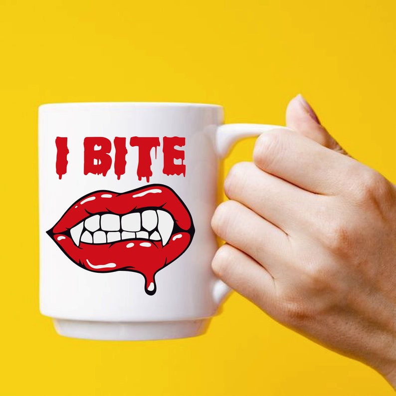 K&ouml;nnte beinhalten: Wei&szlig;e Keramik-Kaffeetasse mit einer roten und wei&szlig;en Illustration eines Vampirmundes mit Z&auml;hnen und dem Text "I Bite".