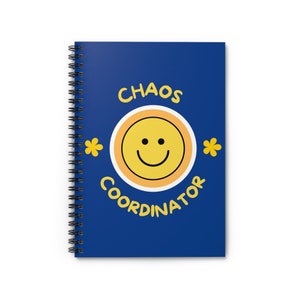 May include: A blue spiral notebook with the text "CHAOS COORDINATOR" in yellow letters. A yellow smiley face with a white outline is in the center of the notebook.