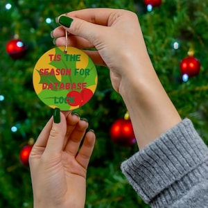Può includere: Un addobbo natalizio rotondo con un design a foglia di agrifoglio verde e il testo "Tis the season for database lock".