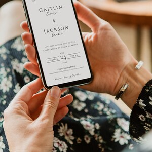 May include: A digital wedding invitation on a smartphone screen. The invitation is for Caitlin Lewis and Jackson Broke, with the date and time of the wedding ceremony: Saturday, August 24, 2023 at 4:00 PM. The wedding will be held at The Flake Garden, 7006 N. Modes Ave, Chicago, Illinois 60617.