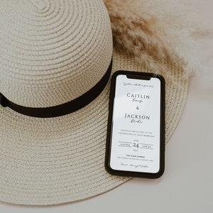 May include: A white smartphone with a black case displays a wedding invitation for Caitlin Lewis and Jackson Bole. The invitation is for Saturday, August 24th, 2023 at 4:00 PM at The Flare Garden. The phone is lying on top of a straw hat.