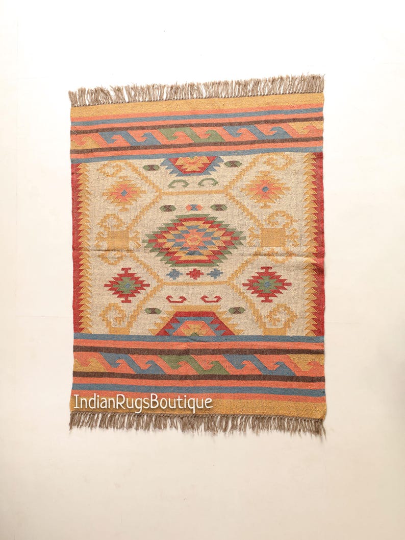 May include: A colorful, geometric patterned rug with a fringe border. The rug is made of natural fibers and has a cream background with red, blue, yellow, and green accents.