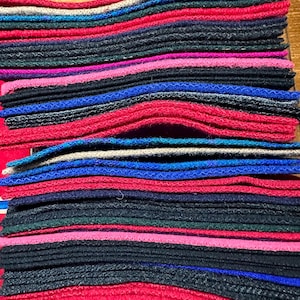 May include: A stack of colorful fabric squares, arranged in a striped pattern. The fabric is a variety of colors, including red, blue, green, black, and pink.