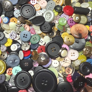 May include: A collection of various buttons in different sizes, colors, and materials. The buttons include black, white, red, blue, and yellow, with some featuring metallic and decorative designs. A variety of shapes and styles are visible.