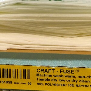 May include: A folded sheet of white Pellon Craft-Fuse 808 interfacing resting on its product box. The box displays the text: Pellon, Craft-Fuse, 808, Machine wash warm, non-chlorine bleach, Tumble dry low or dry clean, 90% Polyester/ 10% Rayon.