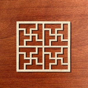 May include: A square, cream-coloured, laser-cut decorative panel featuring a repeating geometric design. The panel is set against a dark wood grain background, creating a contrast between the light panel and the darker surface.