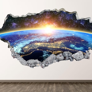Peut inclure: Un sticker mural présentant un effet trompe-l'œil d'un trou irrégulier dans un mur révélant une vue de la Terre depuis l'espace. L'image montre un lever de soleil lumineux sur l'horizon, des lumières urbaines et une galaxie étoilée.