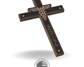 May include: A bronze and black cross with the word "PARAMEDIC" vertically down the center. The cross features a caduceus symbol and stars. The Patriot Design LLC logo is at the bottom.