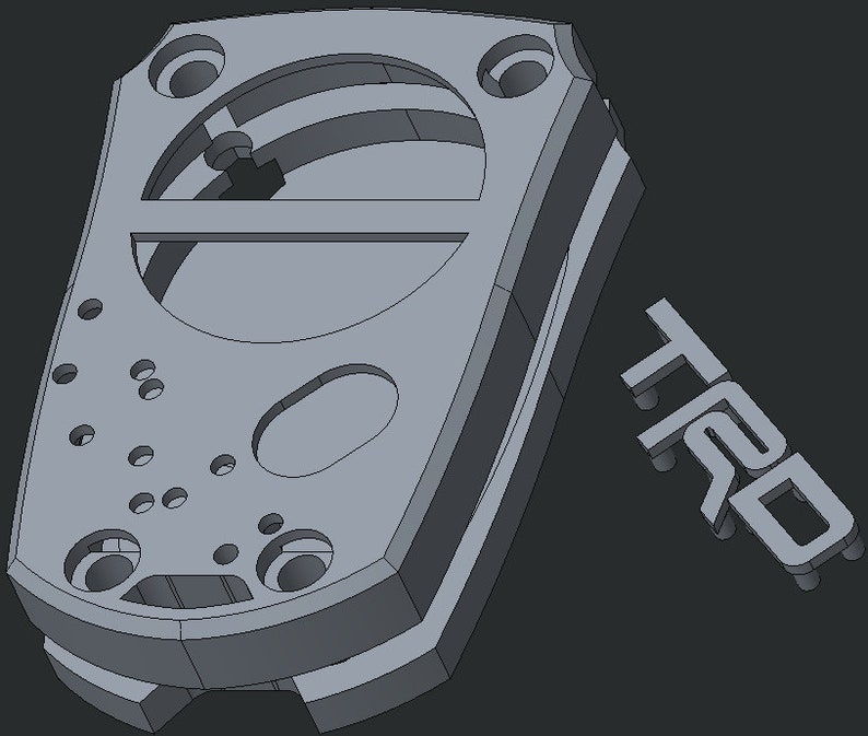 May include: A grey, 3D-rendered component with multiple holes and a curved design. The letters "TRD" are displayed separately, suggesting a mechanical or automotive part. The overall design is geometric and industrial.