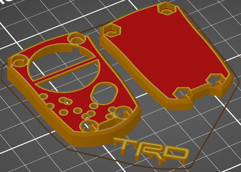 May include: 3D-printed case components in gold and red. The design includes a main body with a circular cutout and several smaller holes, and a separate lid. The word "TRD" is visible in gold.