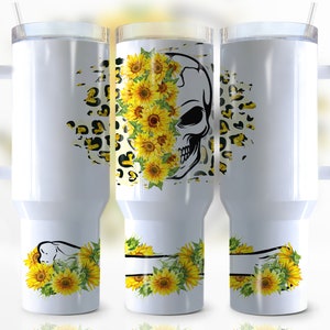 May include: Three white stainless steel tumblers with a black skull design and yellow sunflowers. The skull is partially covered by the sunflowers. The tumblers have a black handle and a straw.