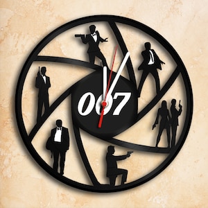 Peut inclure: Horloge en vinyle noir avec des silhouettes de personnages de James Bond et le numéro "007" au centre. Les aiguilles de l'horloge sont rouges et blanches.