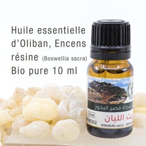 Peut inclure: Une petite bouteille en verre ambré d'huile essentielle avec un bouchon noir, étiquetée "Huile essentielle d'Oliban, Encens résine (Boswellia sacra) Bio pure 10 ml." À côté de la bouteille, plusieurs morceaux de résine jaune pâle.
