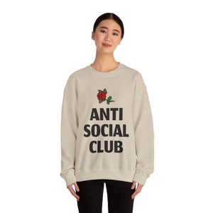 May include: A beige sweatshirt with a black rose and the text "ANTI SOCIAL CLUB" printed on the front.