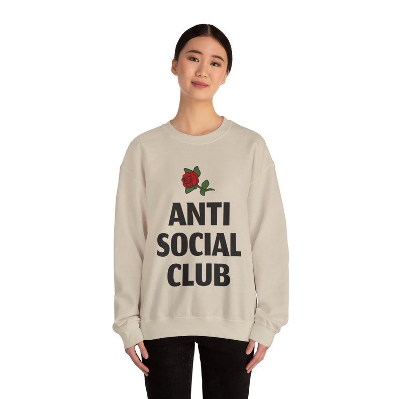May include: A beige sweatshirt with a black rose and the text "ANTI SOCIAL CLUB" printed on the front.