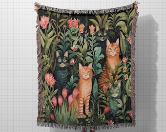 May include: A woven throw blanket featuring a whimsical illustration of cats amidst lush foliage and flowers. The cats are depicted in shades of orange, green, and black against a dark background. The blanket has a fringed edge.