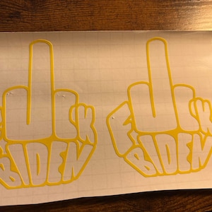 May include: Two yellow vinyl stickers with a middle finger gesture and the text "F**K BIDEN" in a stylized font.